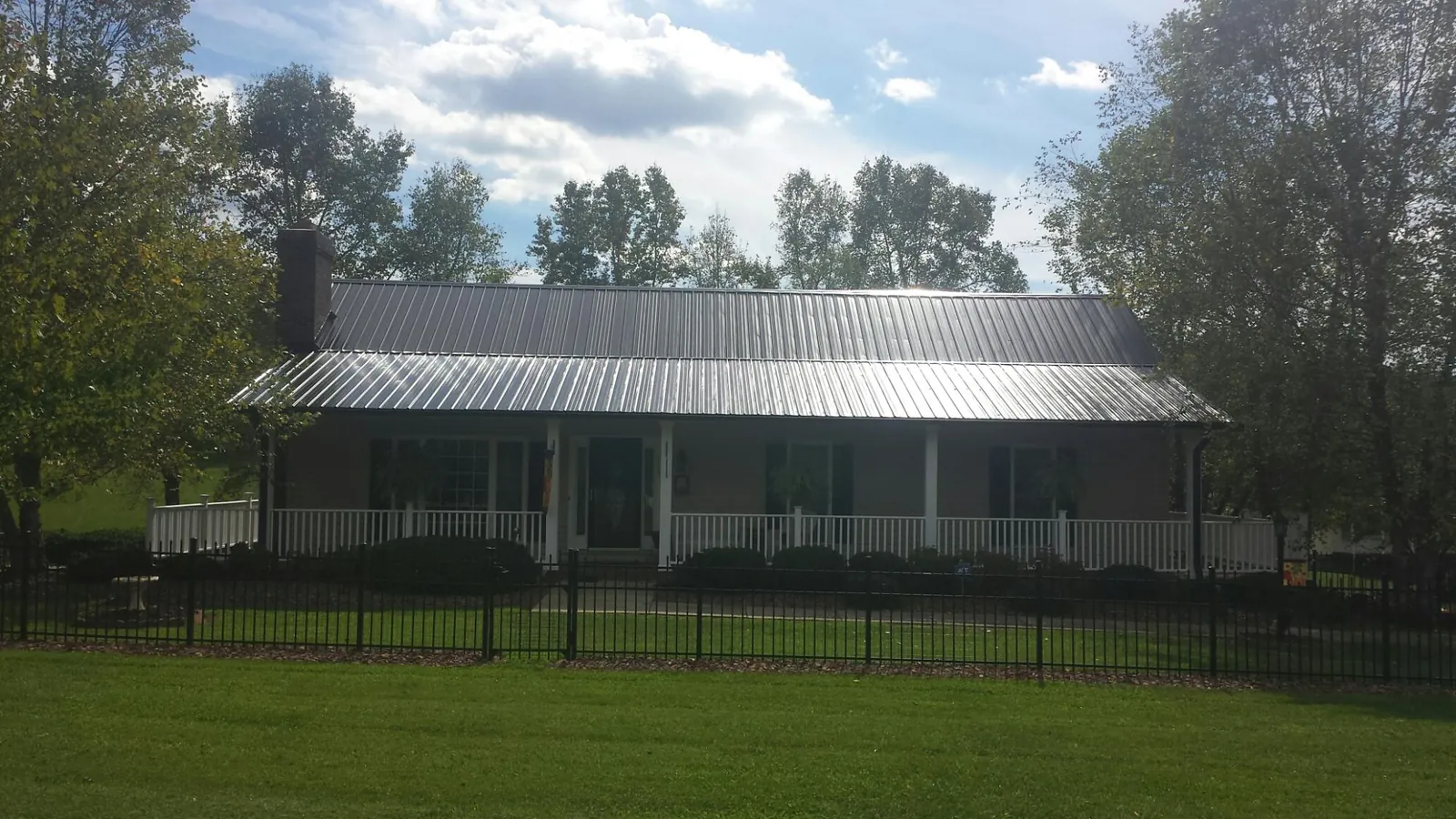 Gray metal roof on a brick ranch with a full width front porch — Gutter Guard Installation work by our crew in Economy