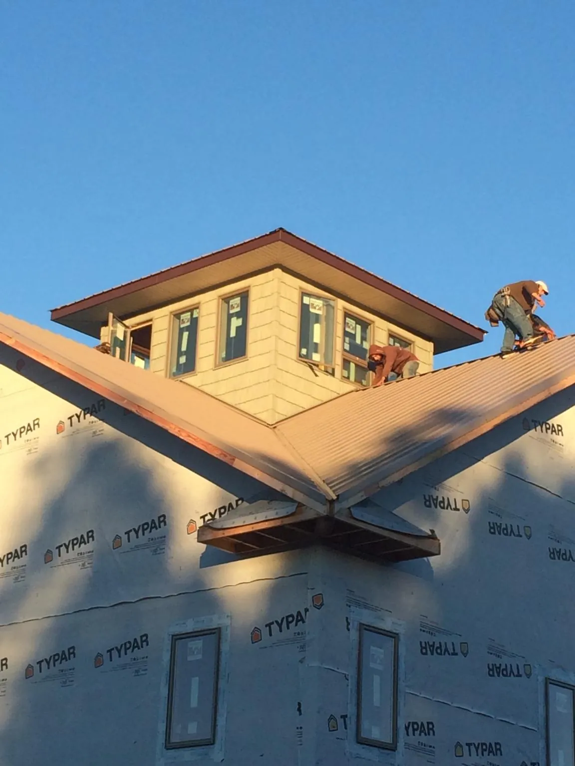 Roofers working around a rooftop cupola on a new metal roof at sunset — Roof Waterproofing in Economy by Roofing Brothers